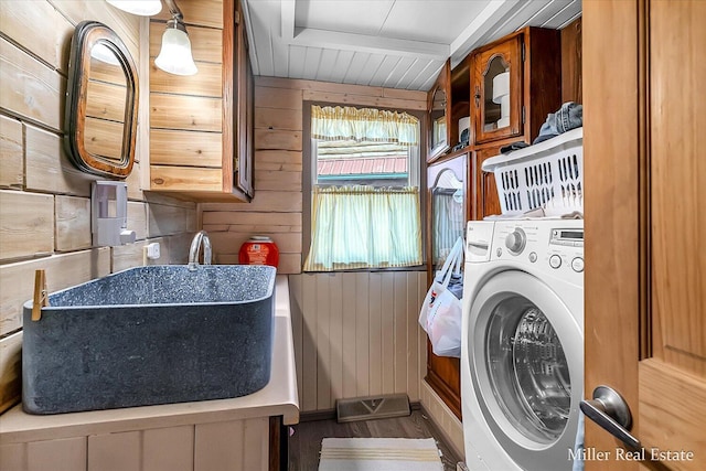 laundry area featuring a sink, washer / dryer, and wood walls