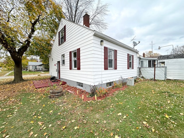 view of side of property featuring a chimney and a yard