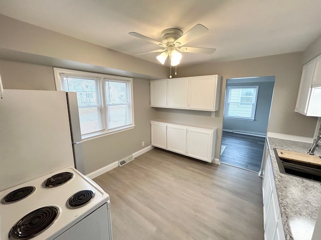 kitchen featuring white electric range oven, a ceiling fan, a sink, light wood-style floors, and freestanding refrigerator