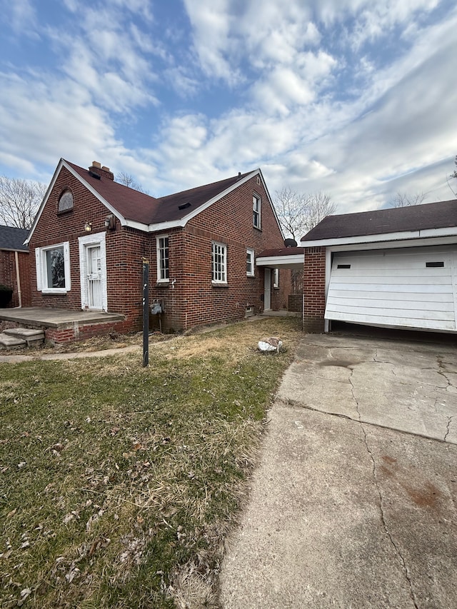 view of property exterior featuring brick siding, a garage, a lawn, and concrete driveway