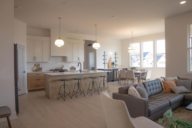 8120 Byron Depot Dr SW, Byron Center, MI 49315 - kitchen featuring light wood-style floors, open floor plan, light countertops, a breakfast bar area, and backsplash