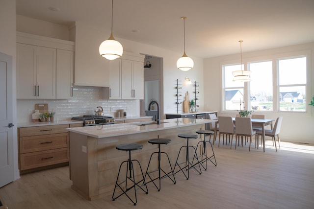 8120 Byron Depot Dr SW, Byron Center, MI 49315 - kitchen with tasteful backsplash, light wood-style flooring, range, a breakfast bar, and a center island with sink