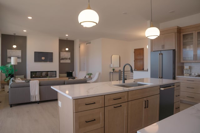 8120 Byron Depot Dr SW, Byron Center, MI 49315 - kitchen featuring appliances with stainless steel finishes, glass insert cabinets, light wood-style floors, pendant lighting, and an island with sink