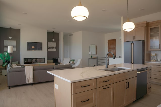 8120 Byron Depot Dr SW, Byron Center, MI 49315 - kitchen featuring appliances with stainless steel finishes, light brown cabinetry, light wood-style flooring, and an island with sink