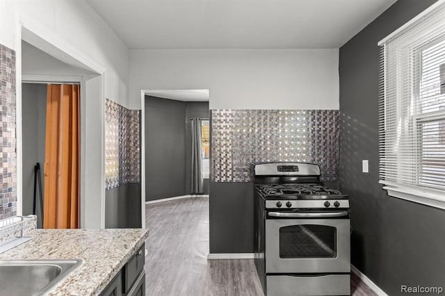 2947 Glynn, Detroit, MI 48206 - kitchen featuring light stone countertops, gas range, baseboards, and wood finished floors