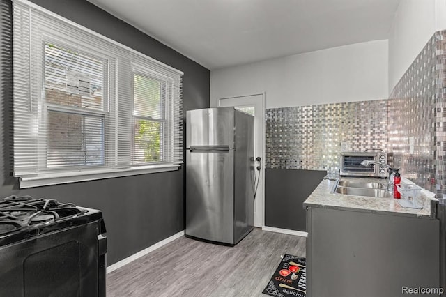 2947 Glynn, Detroit, MI 48206 - kitchen featuring black gas range, baseboards, a sink, light wood finished floors, and freestanding refrigerator