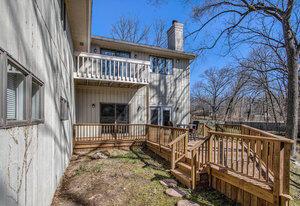 rear view of house featuring a wooden deck, a chimney, and a balcony