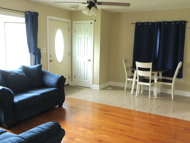 living room with ceiling fan, light tile patterned floors, and baseboards