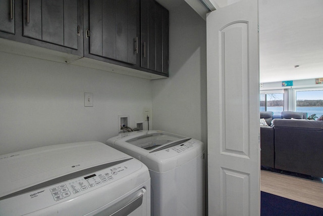 washroom with cabinet space, washing machine and dryer, and wood finished floors