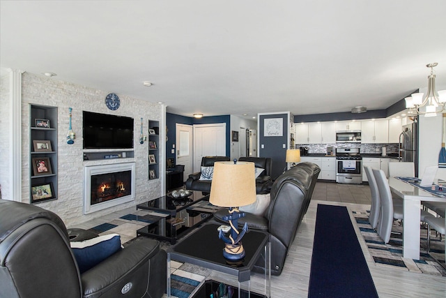 living area featuring a fireplace, built in shelves, and a notable chandelier