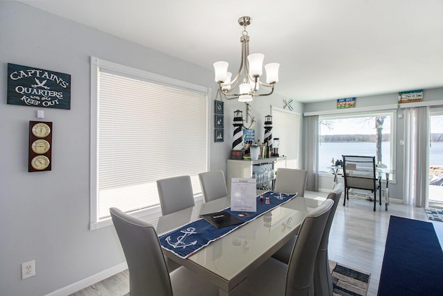 dining space with baseboards, wood finished floors, and a chandelier