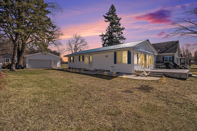 back of property at dusk featuring an outdoor structure, metal roof, a detached garage, a patio, and a lawn