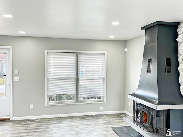 unfurnished living room with baseboards, wood finished floors, a healthy amount of sunlight, and recessed lighting