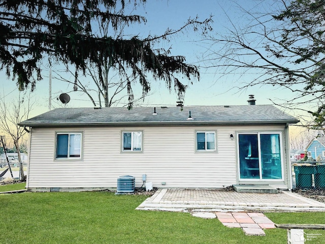 rear view of property featuring roof with shingles, fence, central AC unit, a yard, and a patio area