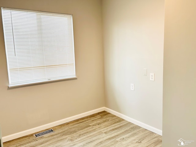 unfurnished room with light wood finished floors, baseboards, and visible vents