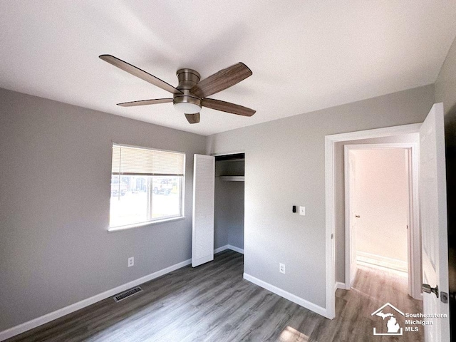 unfurnished bedroom with baseboards, visible vents, a closet, and wood finished floors