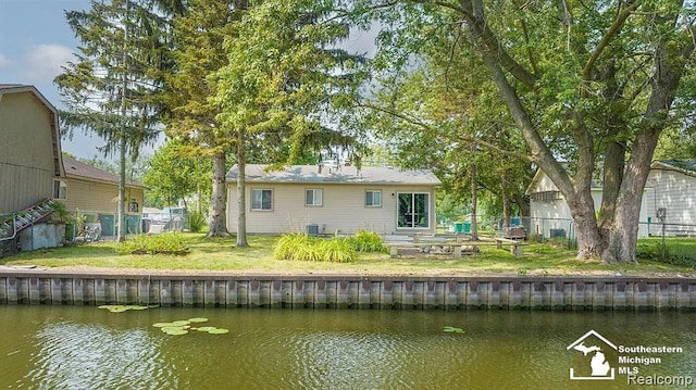 rear view of property featuring a water view and a yard