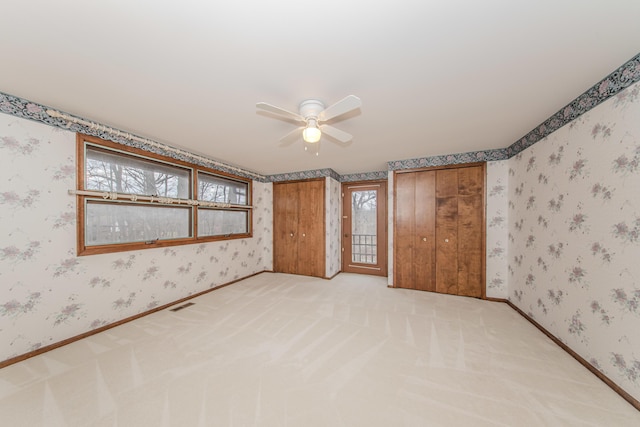 4710 Cove Rd, West Bloomfield, MI 48323 - unfurnished bedroom with wallpapered walls, a ceiling fan, light colored carpet, access to exterior, and two closets
