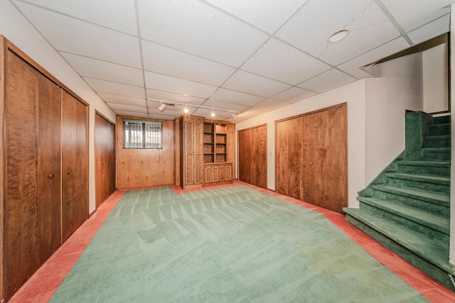 4710 Cove Rd, West Bloomfield, MI 48323 - below grade area with built in shelves, stairway, a paneled ceiling, wooden walls, and light colored carpet