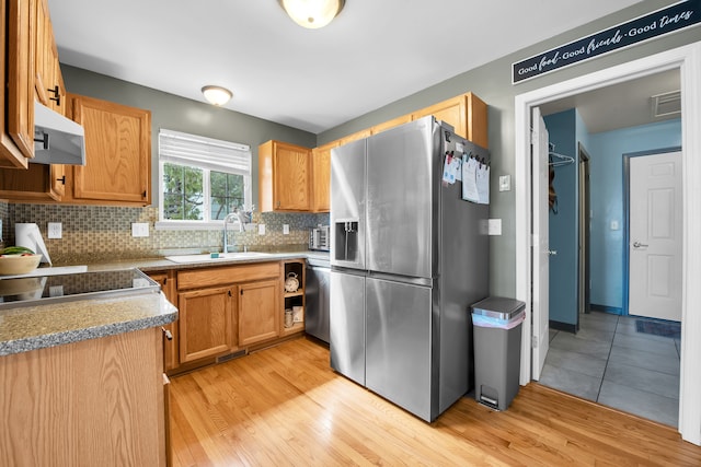 kitchen featuring stainless steel fridge, a sink, light wood-style floors, backsplash, and extractor fan