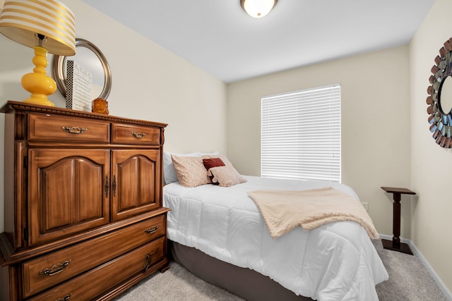 bedroom with light colored carpet and baseboards