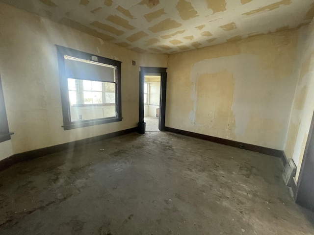 spare room with baseboards and unfinished concrete flooring