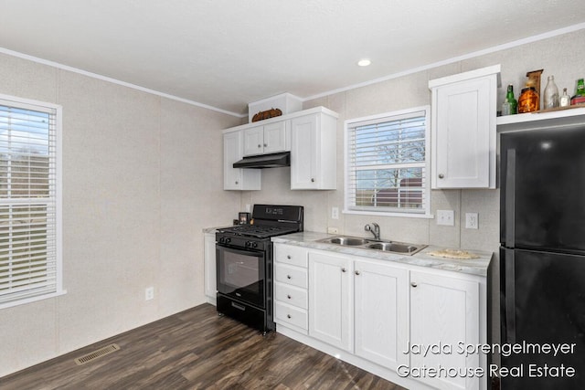 kitchen featuring light countertops, under cabinet range hood, a sink, visible vents, and black appliances