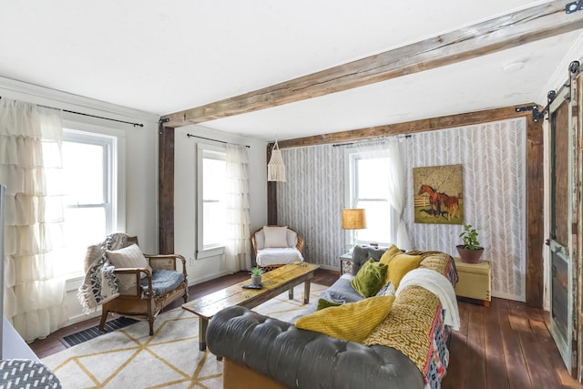 living room with beam ceiling, a barn door, baseboards, visible vents, and hardwood / wood-style floors