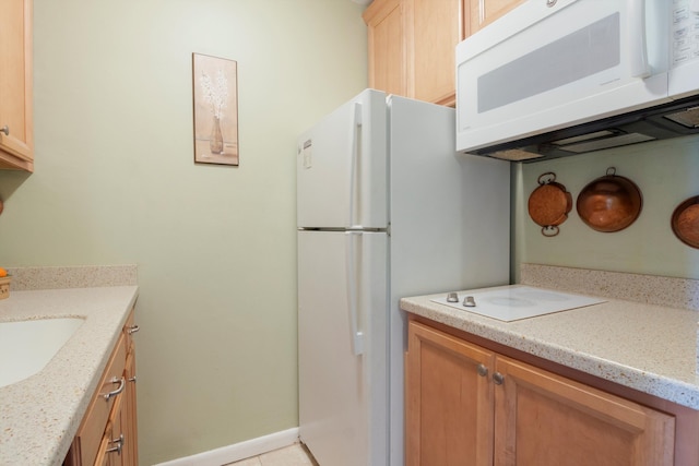 kitchen featuring baseboards, white microwave, and a sink