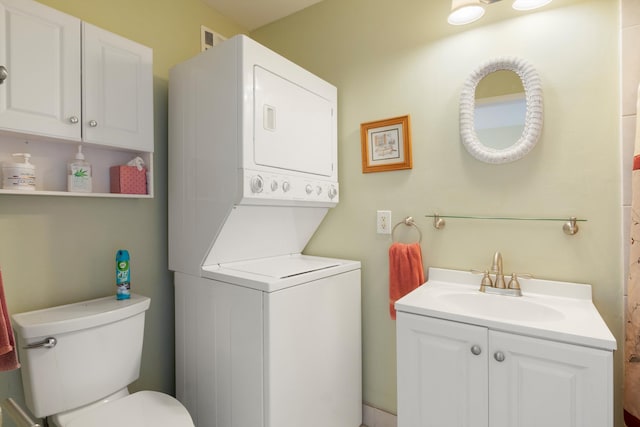 bathroom with stacked washer and dryer, toilet, and vanity