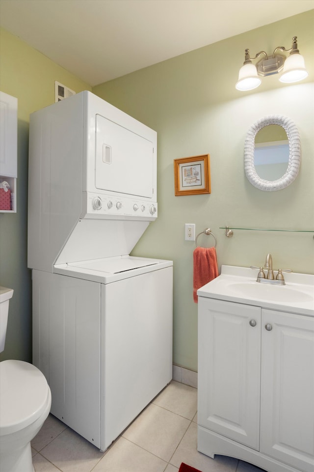 bathroom with stacked washer and dryer, toilet, tile patterned flooring, and vanity