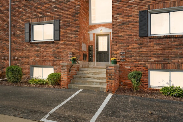 entrance to property featuring brick siding and uncovered parking