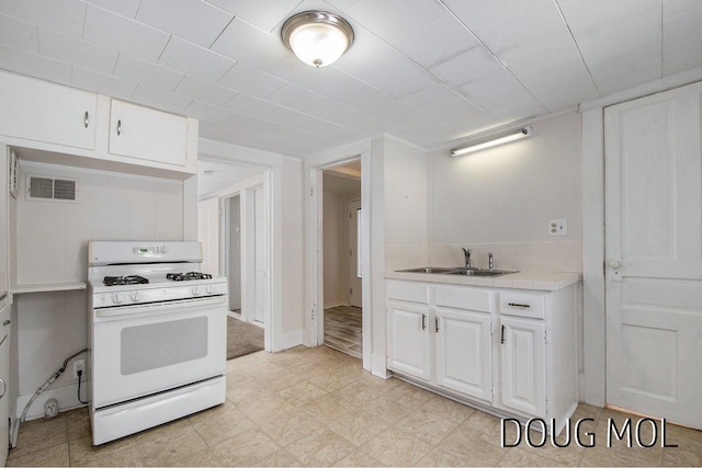 2255 Gaynor Ave NW, Grand Rapids, MI 49544 - kitchen featuring white range with gas stovetop, a sink, tile countertops, and white cabinetry