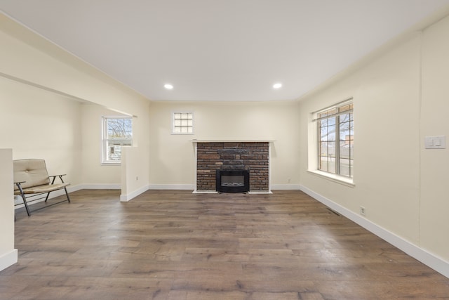 unfurnished living room featuring a stone fireplace, baseboards, recessed lighting, and wood finished floors