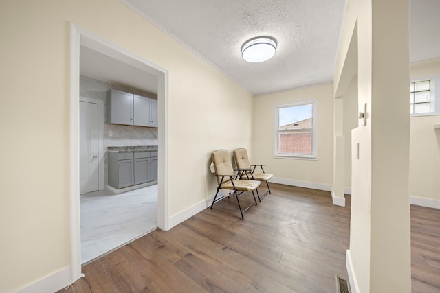 living area with visible vents, a wealth of natural light, wood finished floors, and baseboards