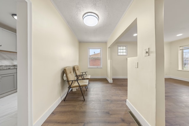 unfurnished room with a textured ceiling, wood finished floors, and a healthy amount of sunlight