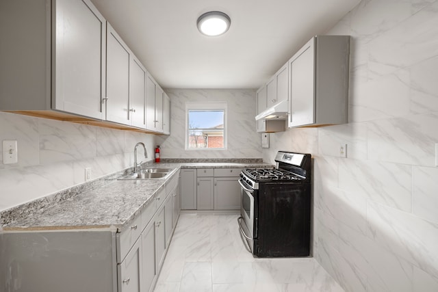 kitchen with stainless steel range with gas cooktop, under cabinet range hood, decorative backsplash, marble finish floor, and a sink
