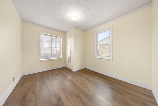 spare room featuring a wealth of natural light, a textured ceiling, hardwood / wood-style flooring, and baseboards