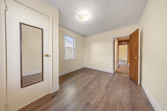 unfurnished room featuring a textured ceiling, baseboards, and wood finished floors