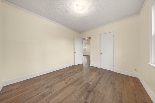 unfurnished bedroom featuring a textured ceiling, baseboards, and wood finished floors
