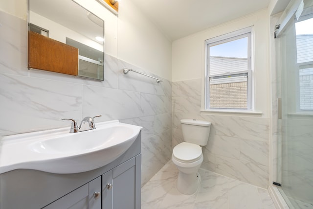 bathroom featuring toilet, marble finish floor, vanity, and a shower with door