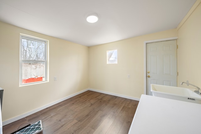 empty room with baseboards, a sink, and wood finished floors