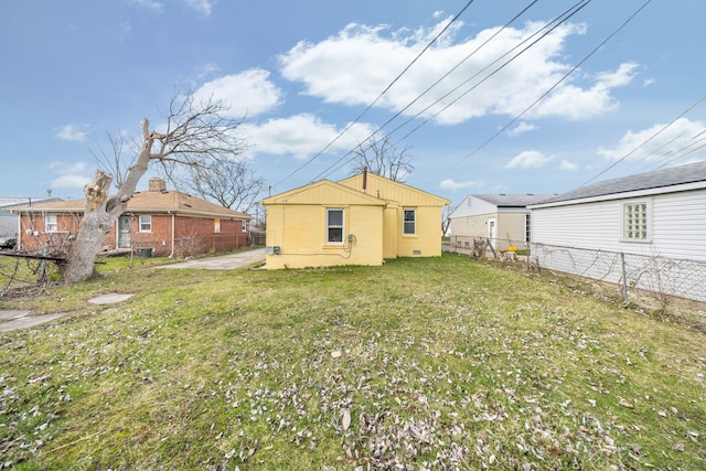 rear view of property featuring fence and a lawn