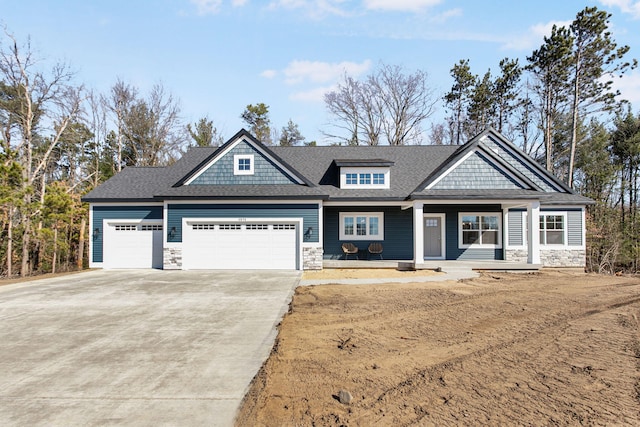 view of front of property with stone siding, driveway, roof with shingles, and an attached garage