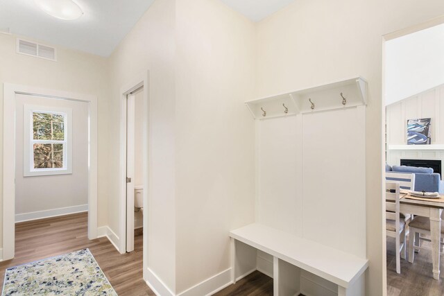 mudroom with wood finished floors, baseboards, a fireplace, and visible vents