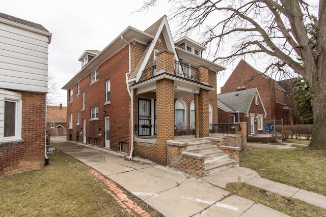 view of front facade with a balcony, covered porch, a front lawn, and brick siding
