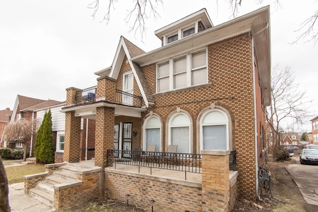 view of front facade featuring covered porch, brick siding, and a balcony