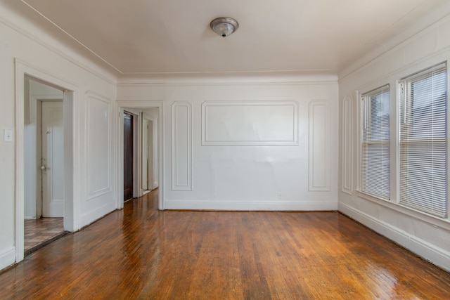 spare room with wood-type flooring, a decorative wall, and ornamental molding