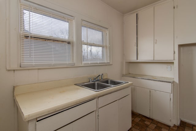 kitchen with white cabinetry, a sink, and light countertops