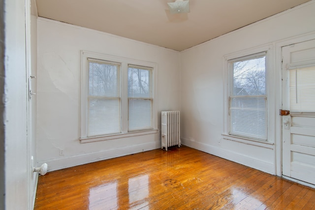 unfurnished room featuring radiator, baseboards, and hardwood / wood-style flooring